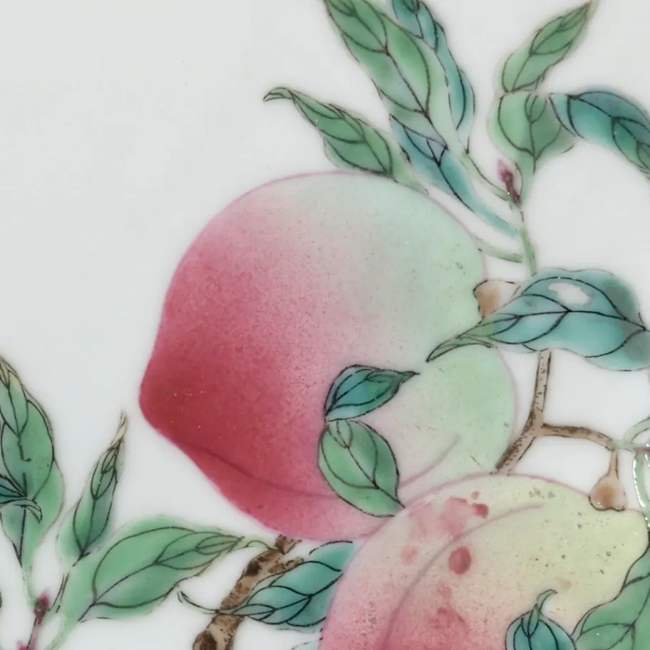 Detail of a Yongzheng famille rose dish: a peach in opaque pink enamel graded through white to pale green, among leaves outlined in black