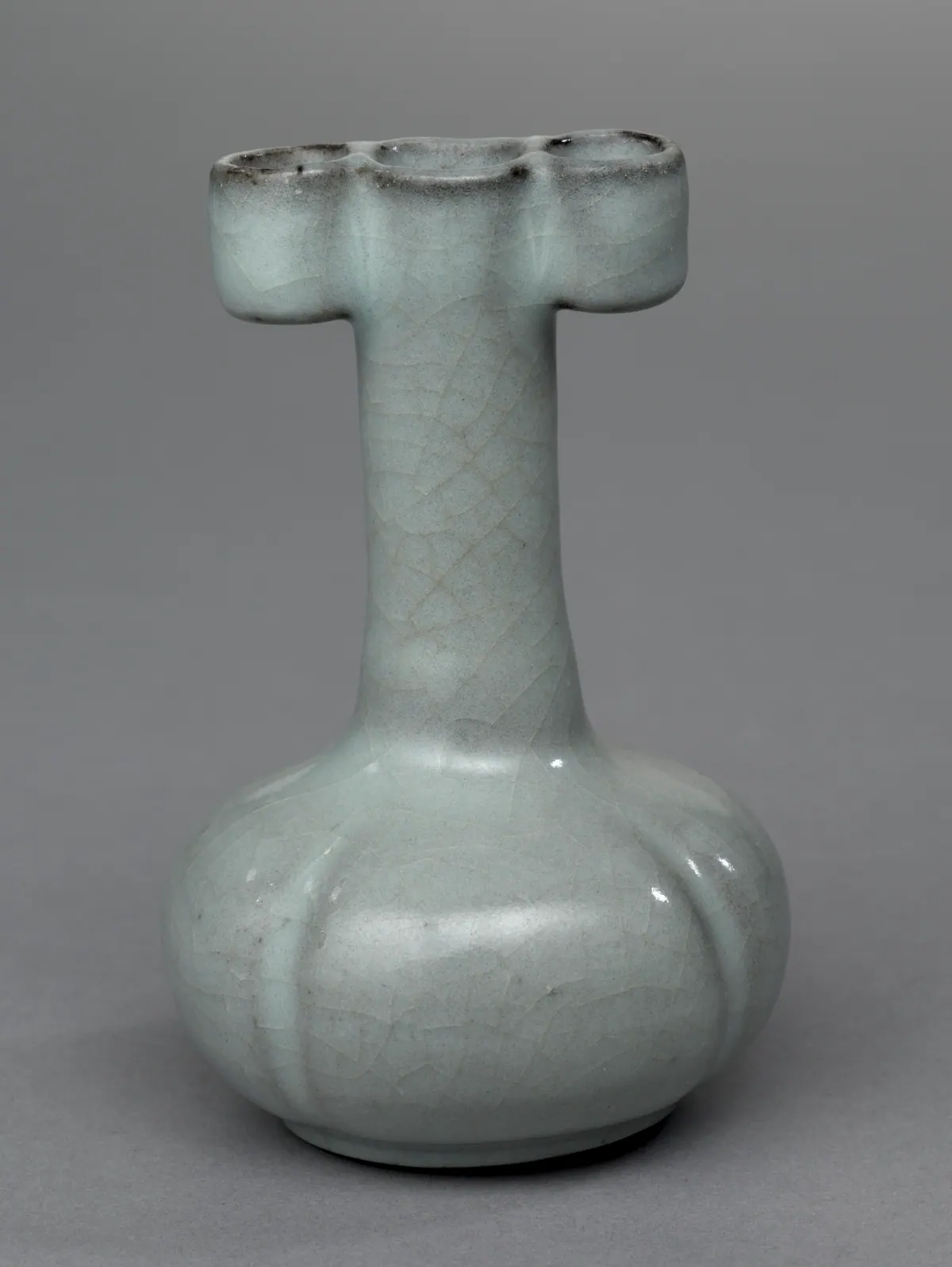A Guan ware arrow vase with a squat lobed body and a tall straight neck, its mouth flanked by two tubular loops, under a pale grey glaze with a fine network of crackle.