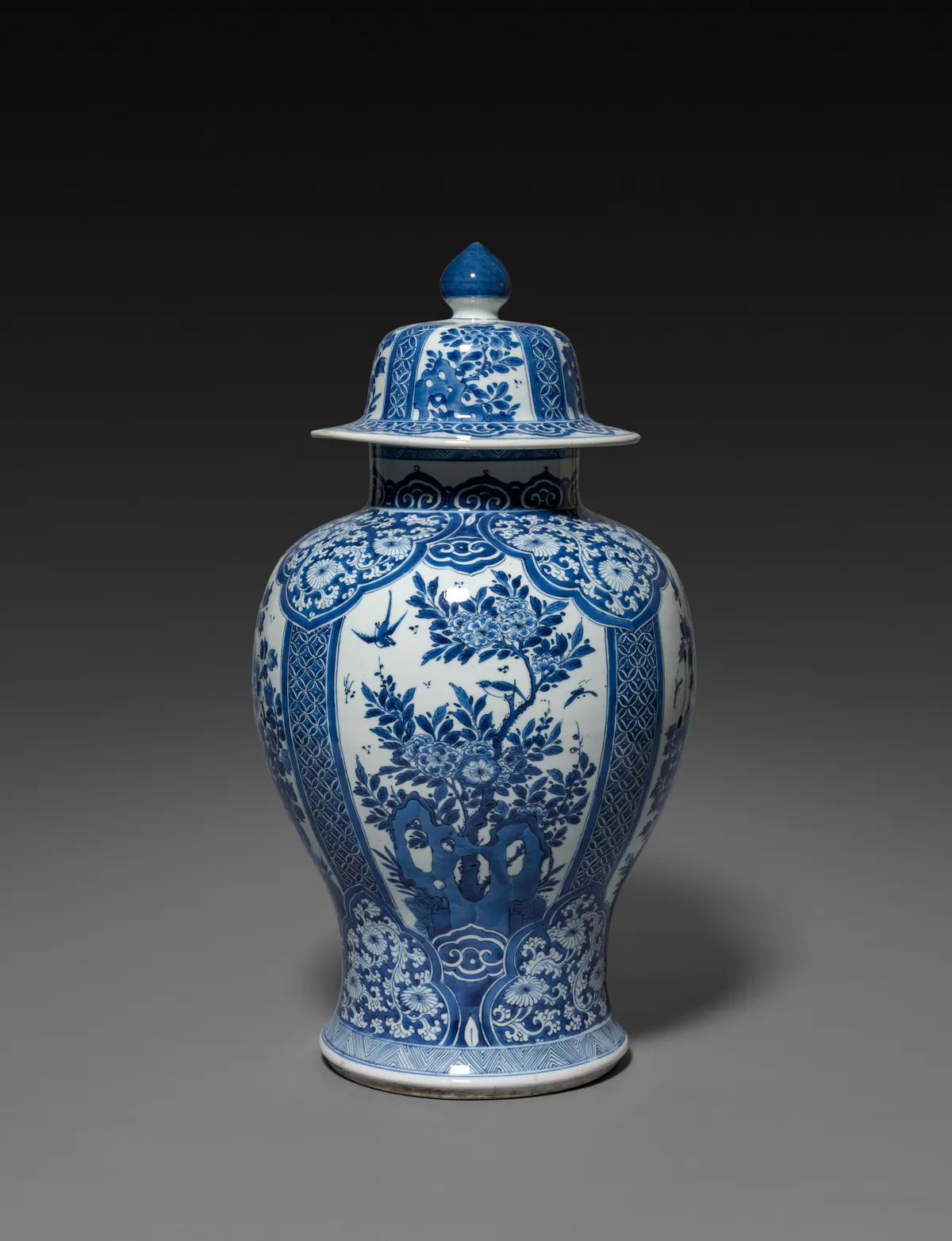 Kangxi period blue and white baluster vase and cover, with panels of flowering branches, birds and a garden rock, framed by diaper and scroll borders in a clear, bright sapphire blue.