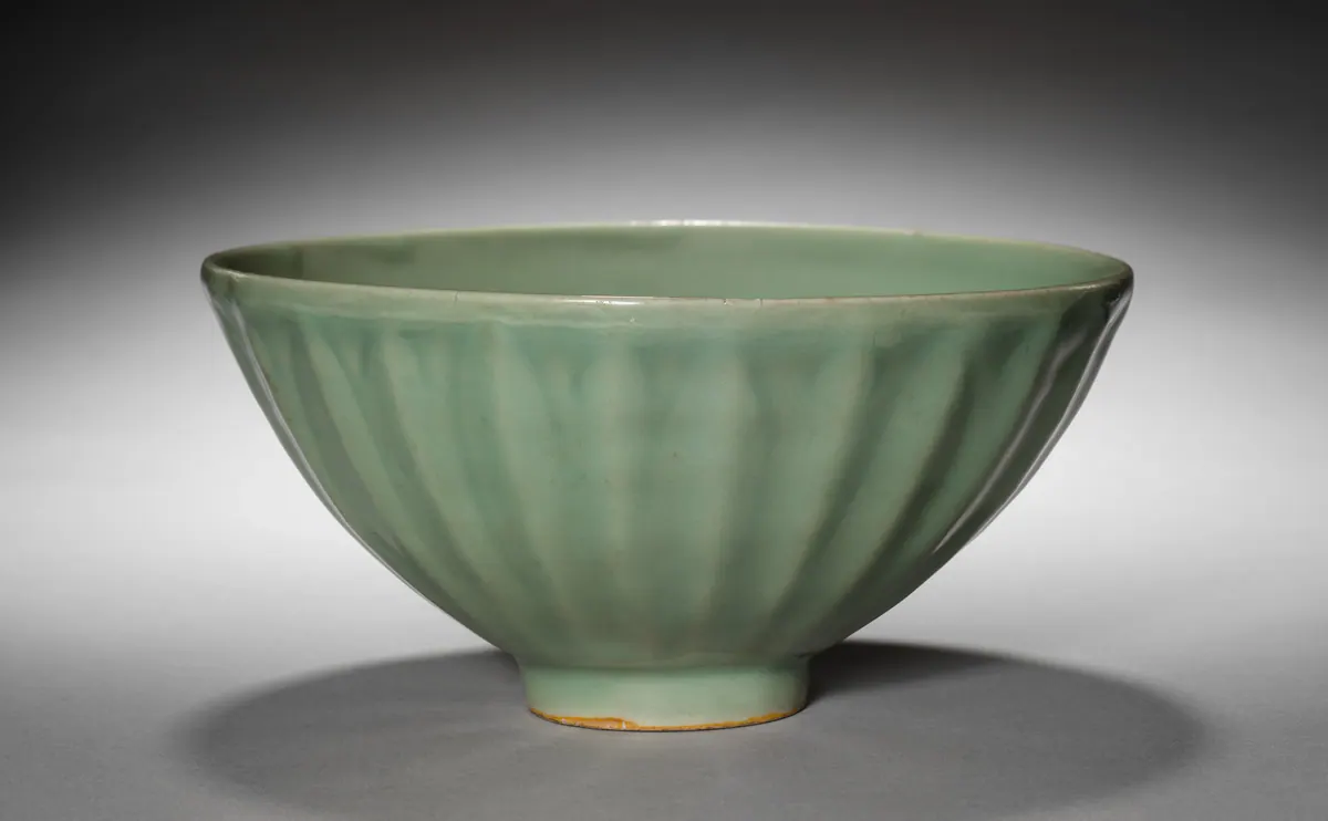 A Longquan celadon bowl on a small foot, its outside formed with tall lotus petals under a thick, glossy sea-green glaze.