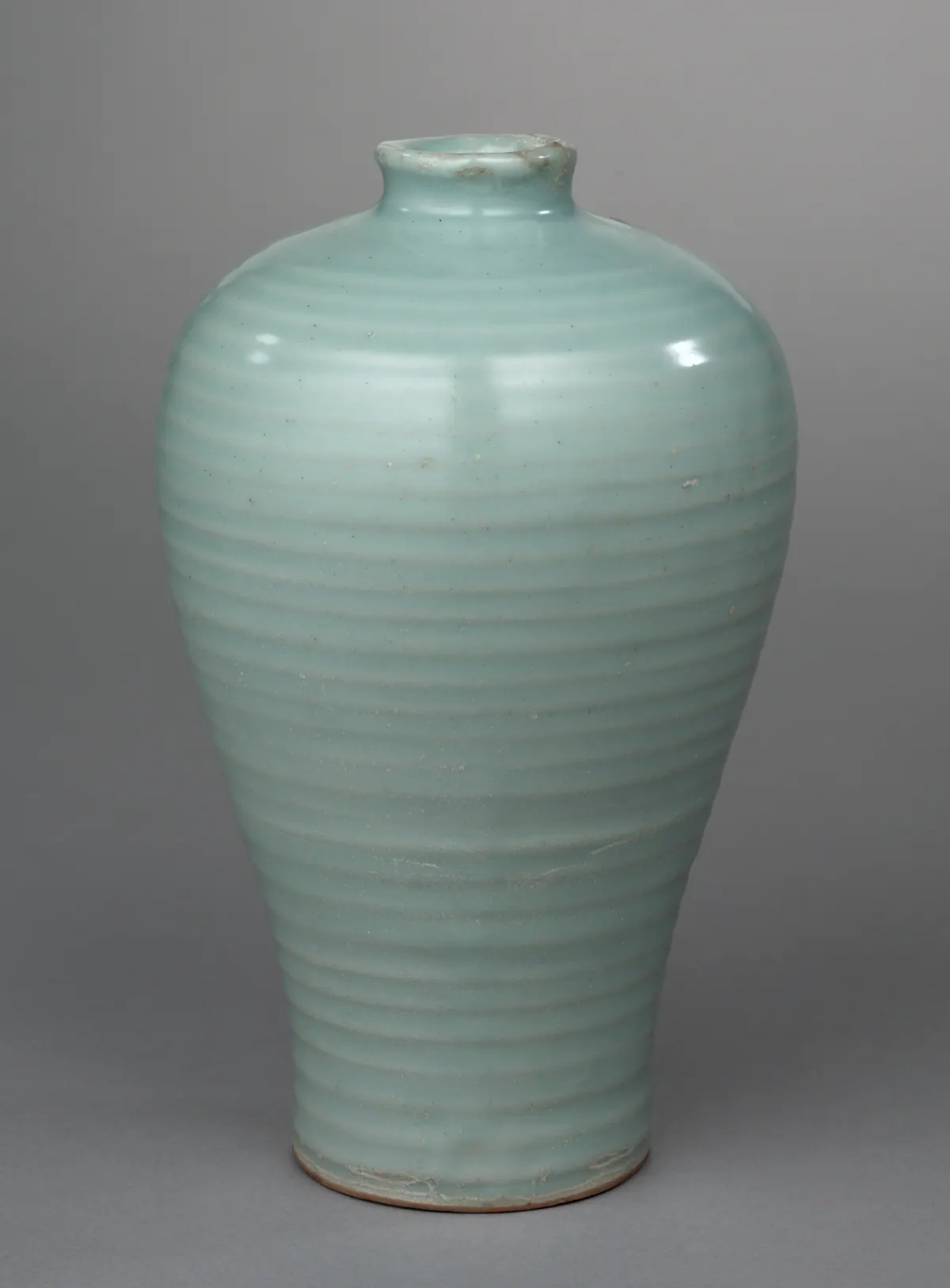 A Longquan celadon meiping vase with a small neck and a tapering body, its thick, soft pale blue-green glaze over a body ribbed with broad horizontal ridges.