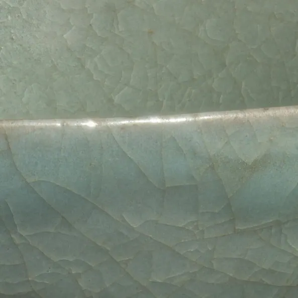 Close-up of the glaze on a Ru brush washer, about 3 cm across: a soft blue-green glaze with a fine, irregular net of crackle on either side of the rim