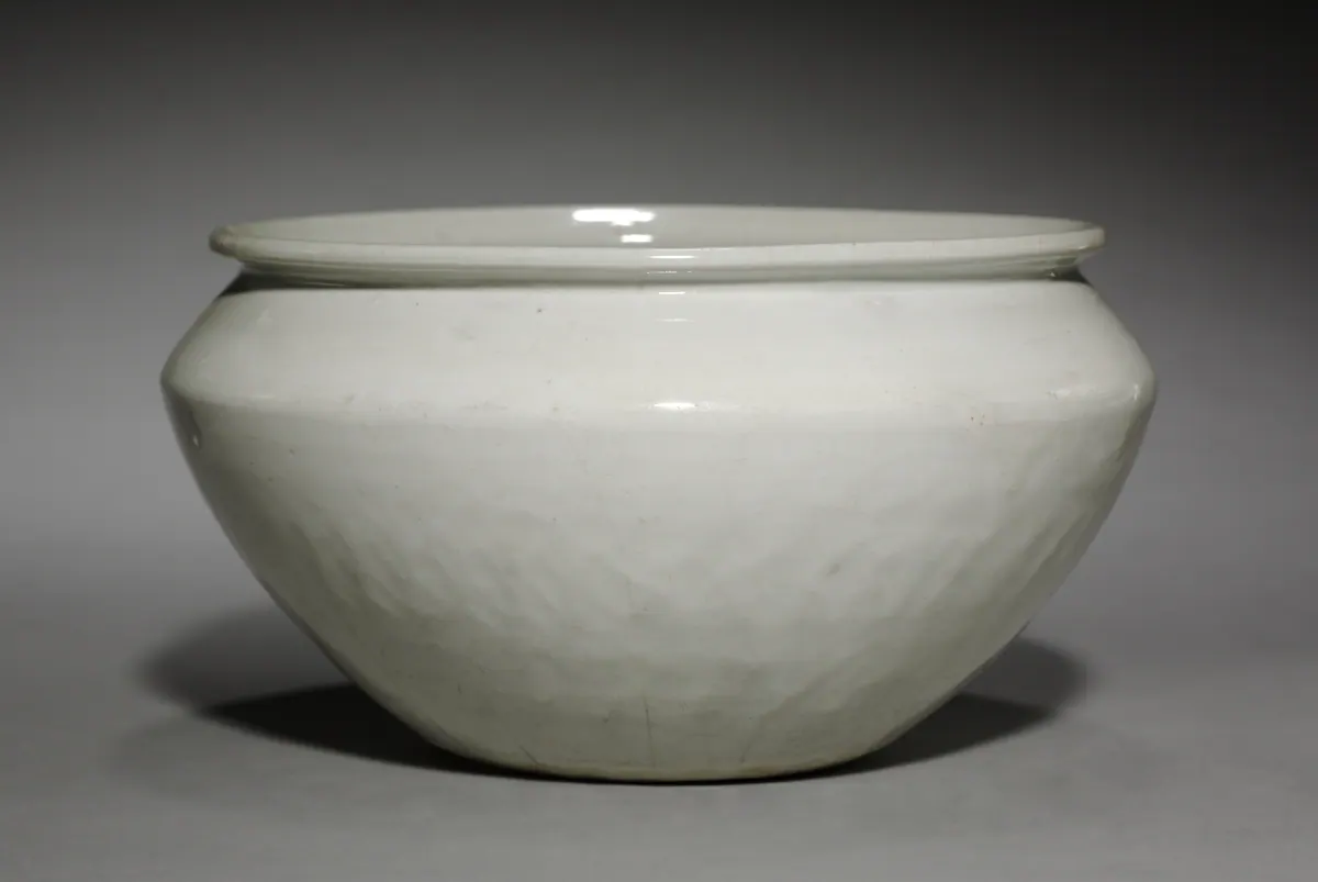A deep white porcelain bowl with an angular shoulder and a rolled rim, covered in a glossy white glaze with fine crackle.