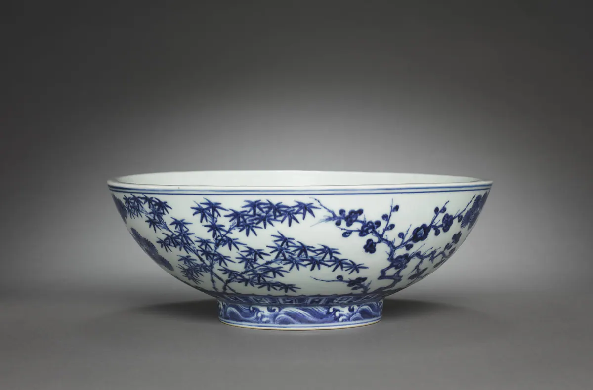 Xuande mark and period blue and white bowl painted with pine, bamboo and flowering plum, the Three Friends of Winter, in strong blue with darker spotting, above a band of waves on the foot.