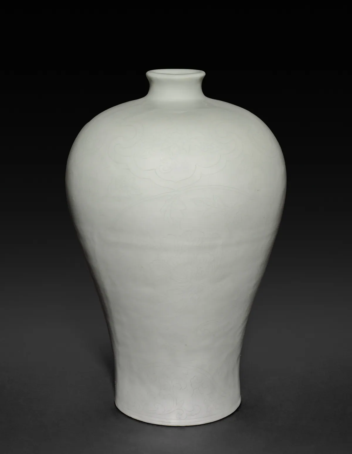 A Yongle white porcelain meiping with a broad, high shoulder tapering to a narrow foot, a very short neck and a small mouth, with faint incised cloud collars and peony sprays under the glaze.