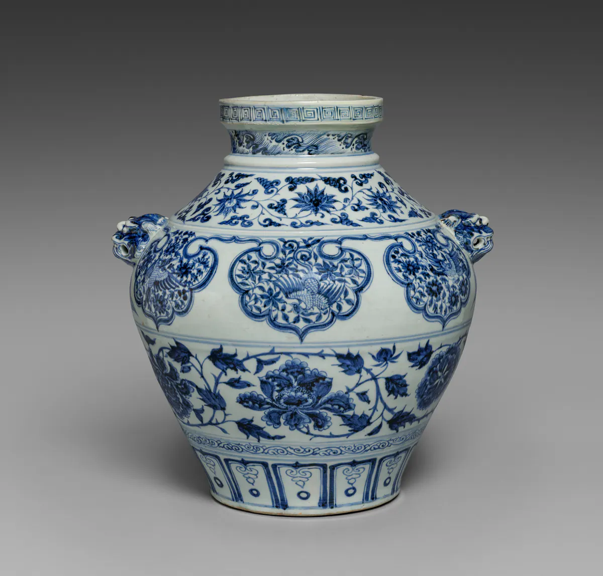 Yuan dynasty blue and white jar with lion-head handles, painted with peony scrolls, phoenixes in lobed panels and a band of petal panels, in a deep, dark cobalt blue.