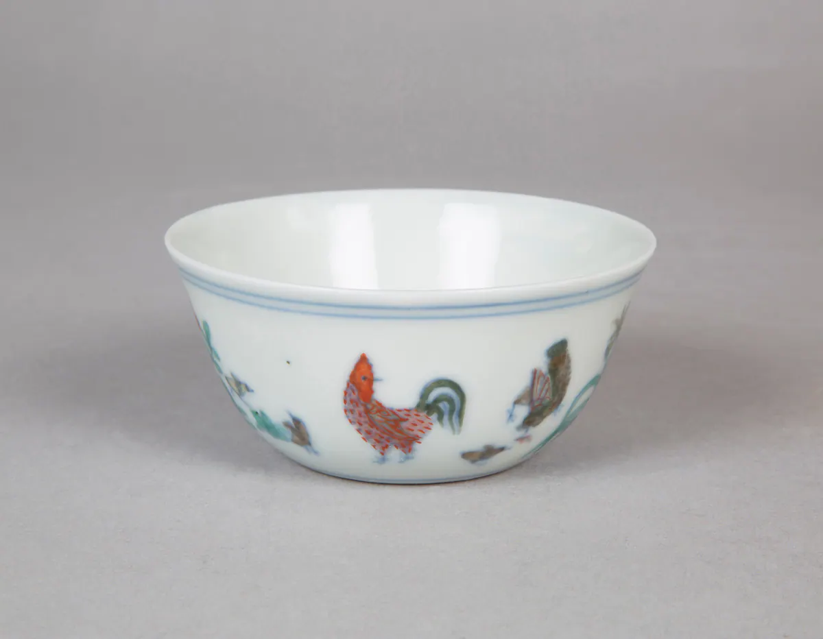 Chenghua mark and period doucai chicken cup, a small thin wine cup painted with a rooster, hen and chicks among plants, outlined in underglaze blue and filled with soft enamels.