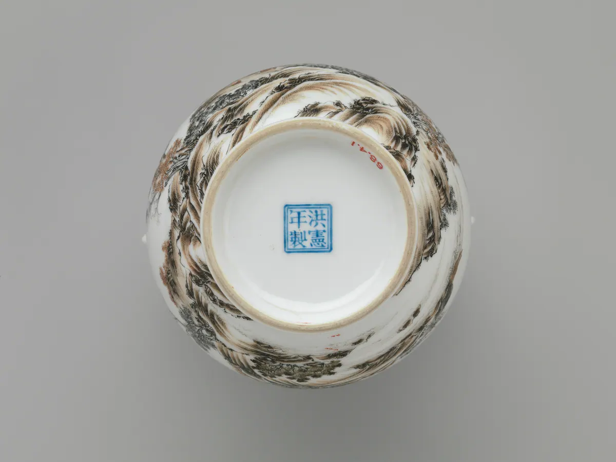 Base of a Republic period porcelain vase, with the four-character mark Hongxian nian zhi in blue enamel inside a square double frame, encircled by landscape painting in black and russet enamels