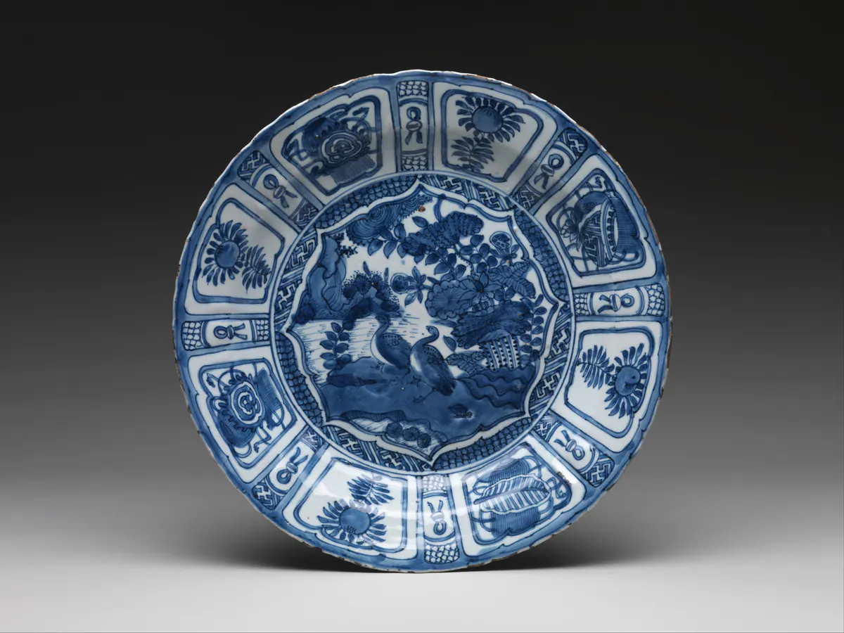 Wanli period kraak dish seen from the front, with geese by a lotus pond in the central medallion and a border of alternating wide and narrow radiating panels in underglaze blue.