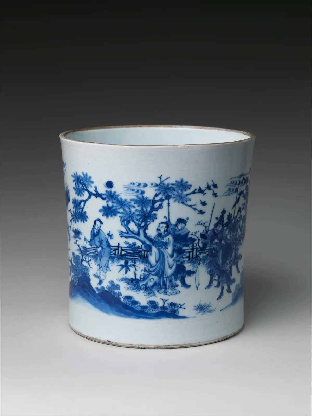 Chongzhen period blue and white brush pot painted with a figure scene under a pine, a fence, warriors with a banner and a moon among clouds, with incised scroll borders at rim and foot.