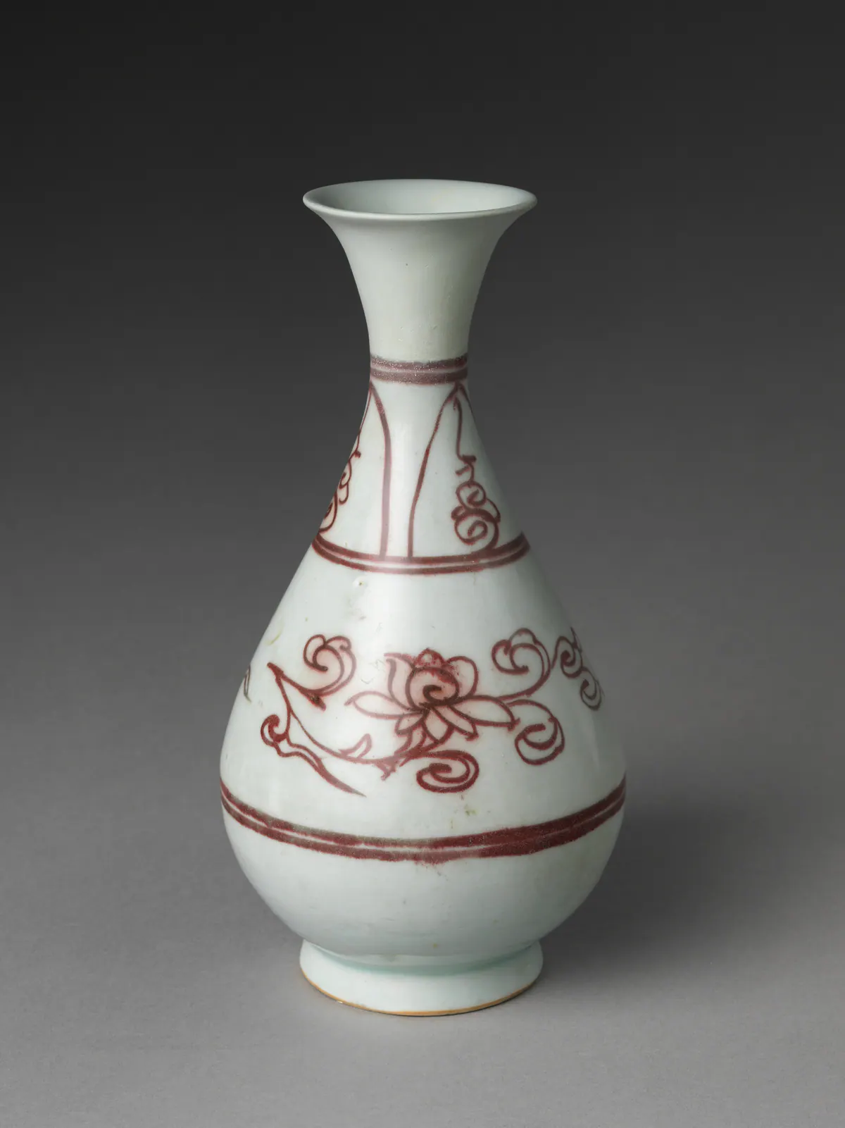 A pear-shaped Yuan porcelain bottle with a flared mouth, painted in underglaze copper red with a flower spray between double bands and pendant panels on the neck.