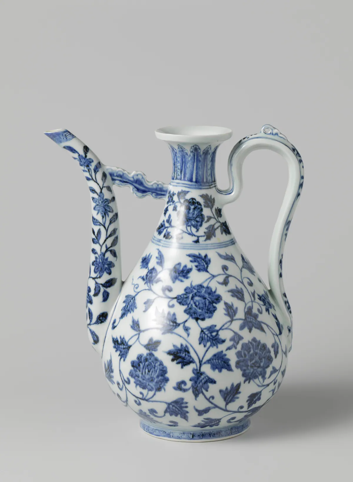 A Yongle blue and white pear-shaped ewer painted with large flower scrolls, its long curving spout braced to the neck by a cloud-shaped strut, with a tall looped handle.